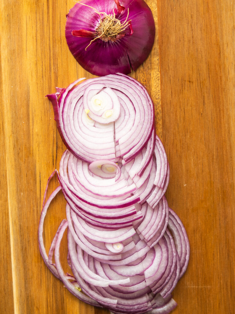 Above view of a thinly sliced red onion on a cutting board