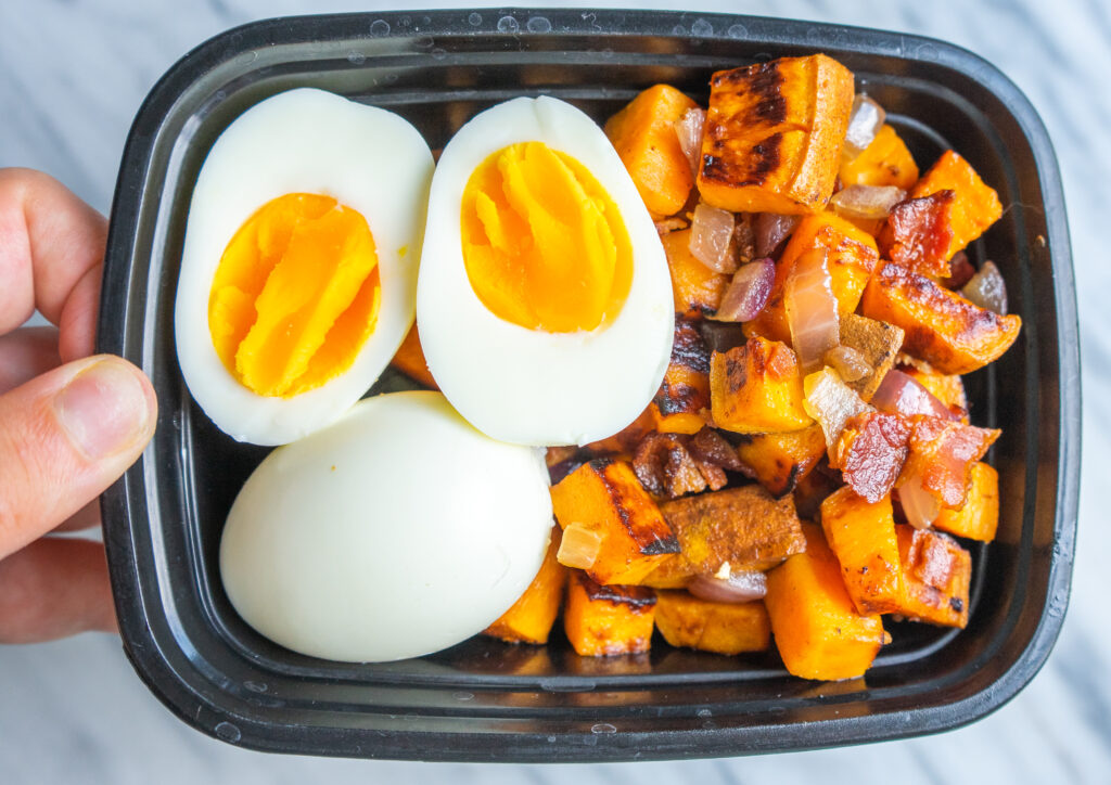 above view of a hand holding a meal prep container with a paleo breakfast inside