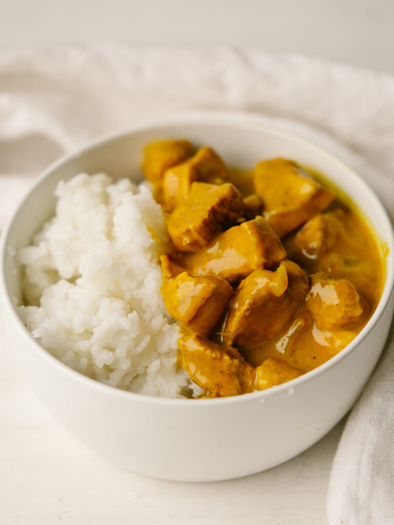 Three quarter view of pumpkin coconut chicken curry in a bowl with white rice