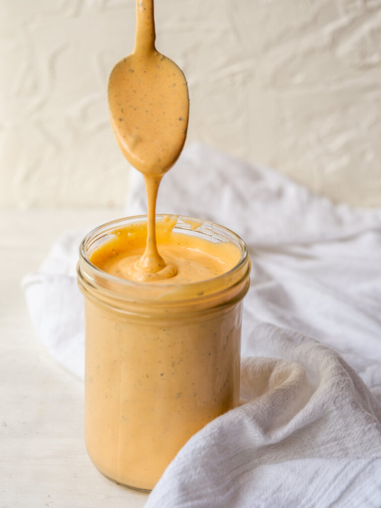 spoonful of buffalo ranch pouring into a jar of the sauce