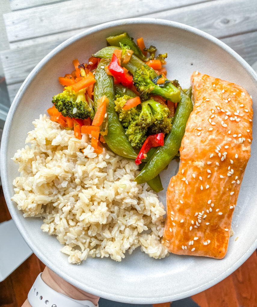 above view sheet pan salmon meal on a plate with veggies and rice