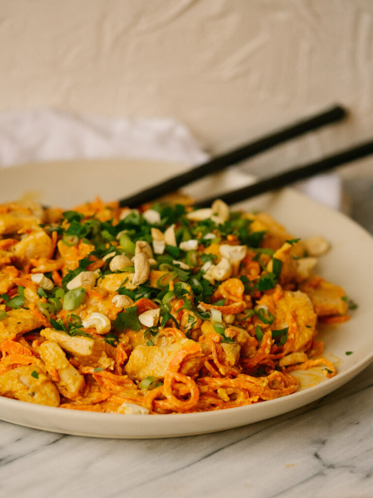 Three quarter view of a plate of carrot noodle pad thai