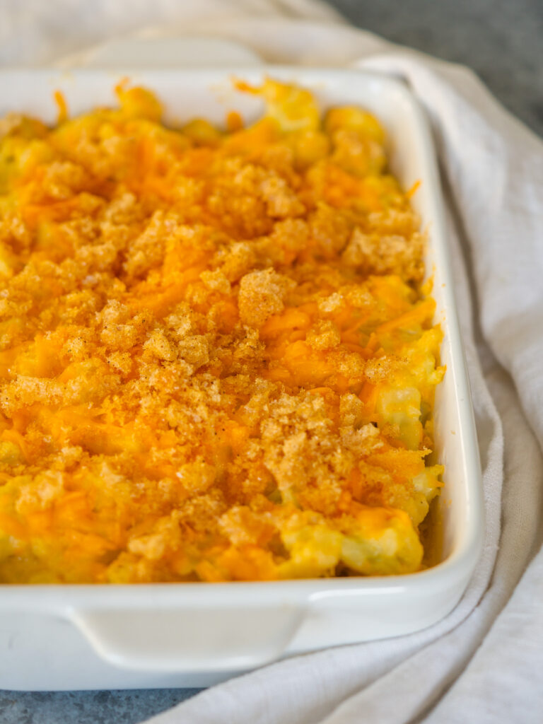 Three quarter view of cauliflower mac and cheese in a baking dish with a crispy top