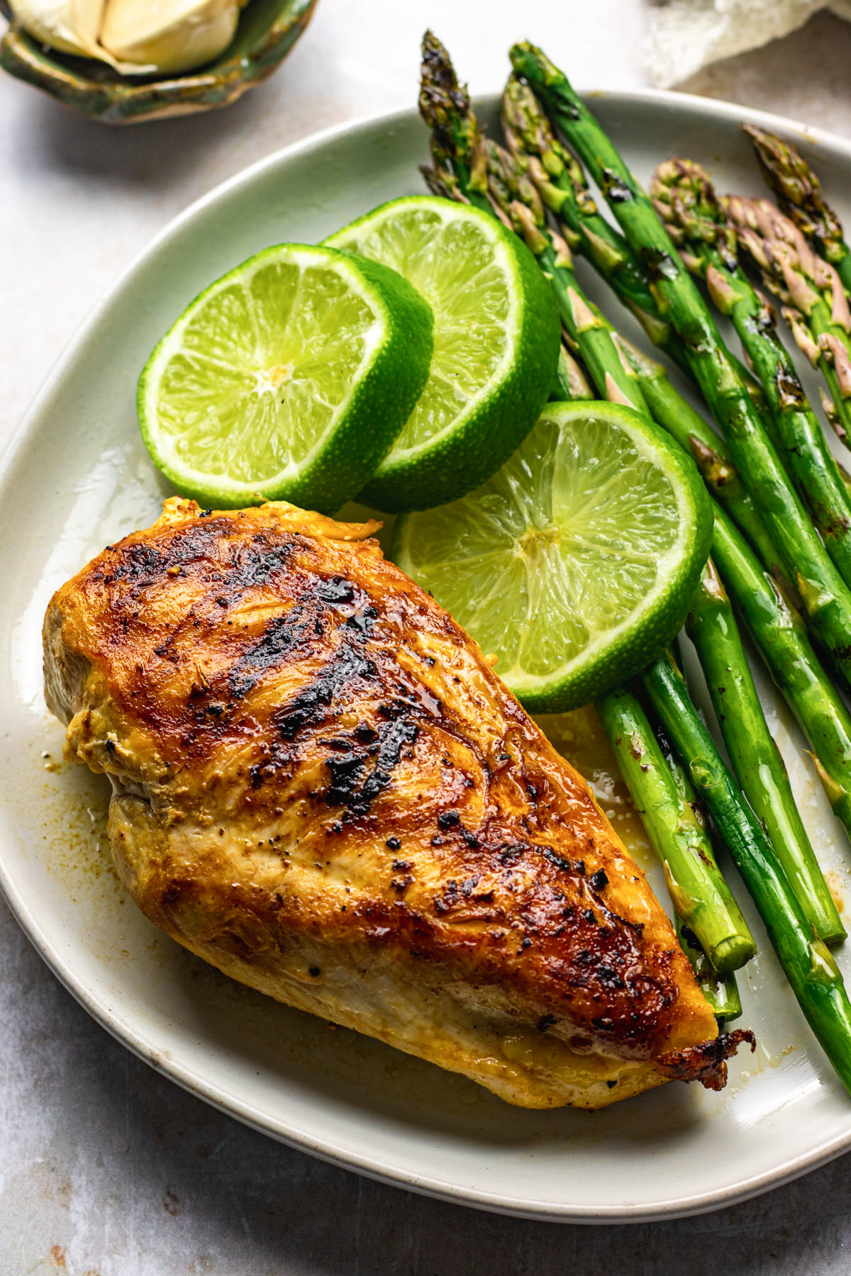 Grilled ginger lime chicken on a plate served asparagus and lime slices