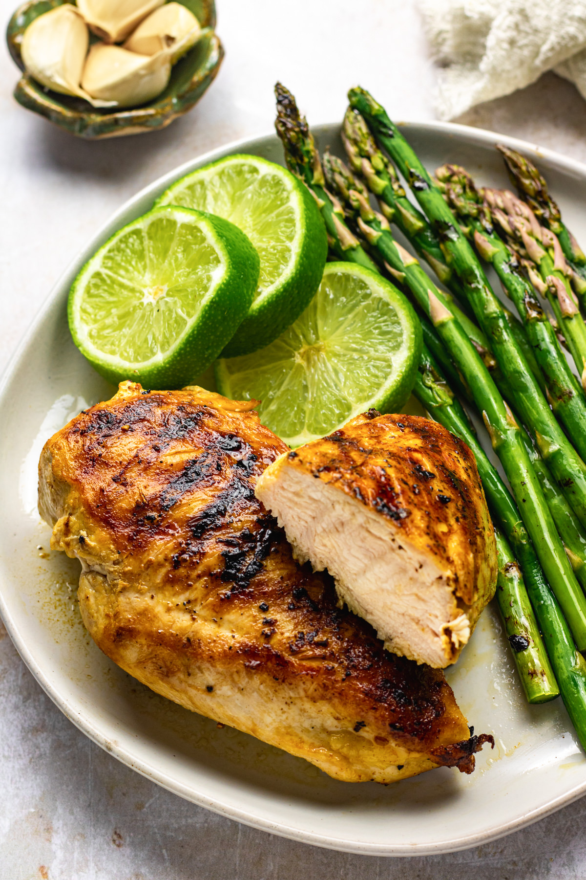 Grilled ginger lime chicken on a plate served asparagus and lime slices