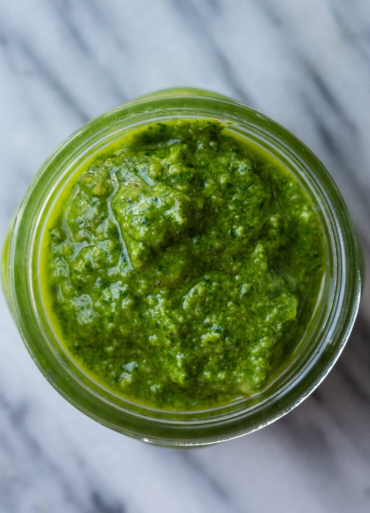 Above view of a bright green walnut pesto sauce in a half pint jar