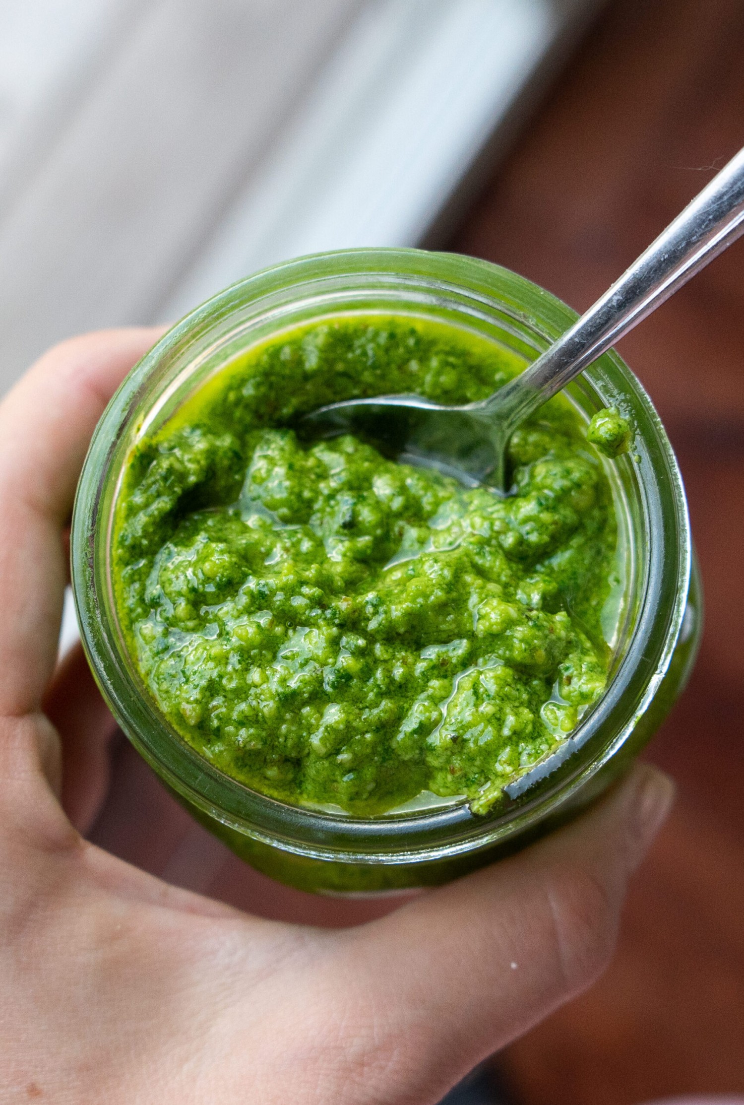 Above view of homemade walnut pesto in a glass jar with a serving spoon