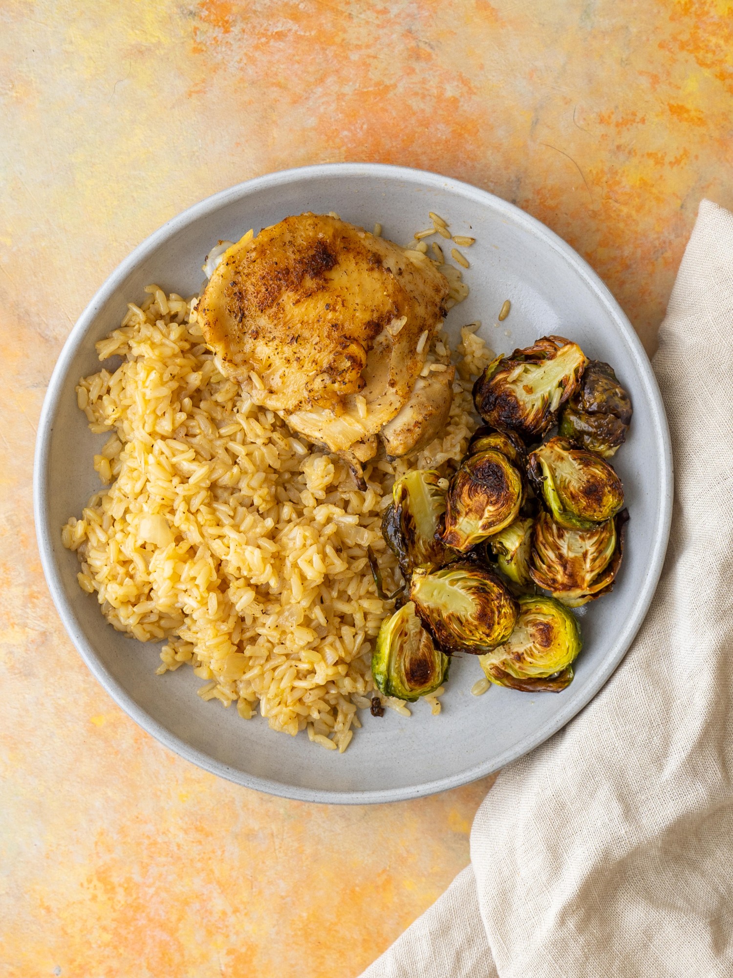 Instant pot chicken thighs and rice on a serving plate with roasted brussels sprouts