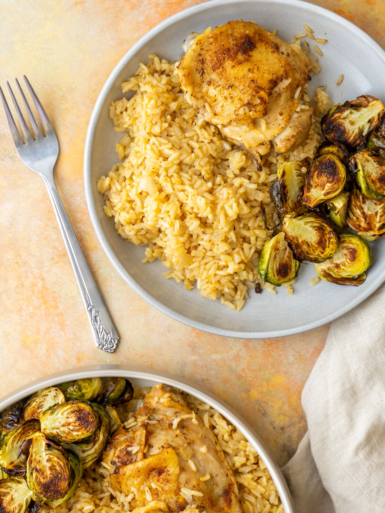 Above view of chicken thighs and rice on a serving plate with brussels sprouts