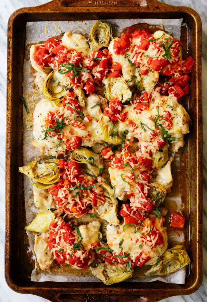 Above view of sheet pan tomato and artichoke chicken with fresh basil