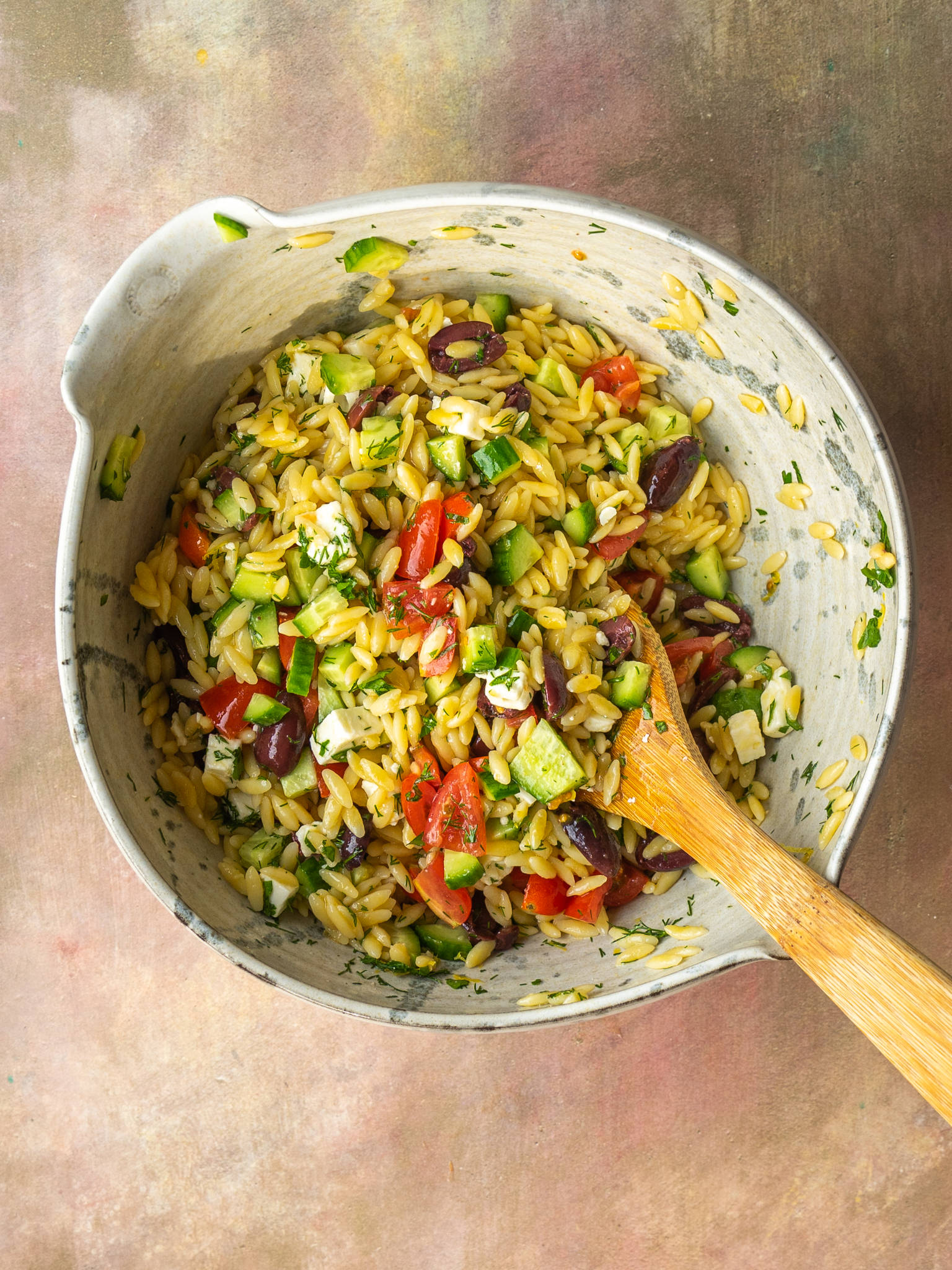 Above view of greek orzo salad in a mixing bowl