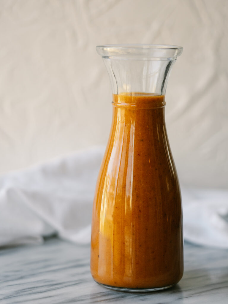 full vertical view of healthy chipotle vinaigrette in a glass bottle