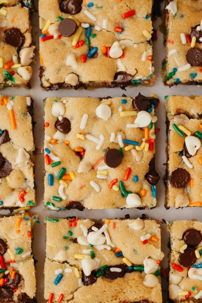 Birthday cake cookie bar squares arranged on a piece of parchment paper
