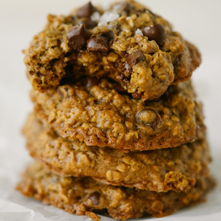 Side view of peanut butter oatmeal chocolate chip cookies stacked up with a bite out of the top cookie