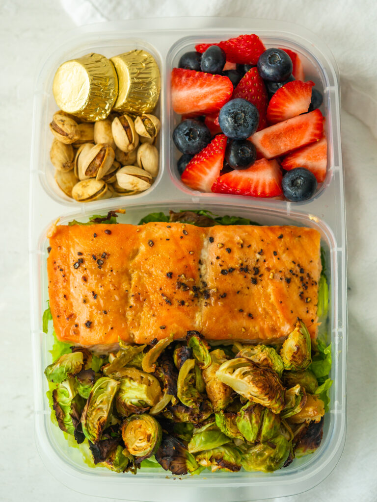 Above view of lunch box with dijon salmon and brussels sprouts with nuts and berries