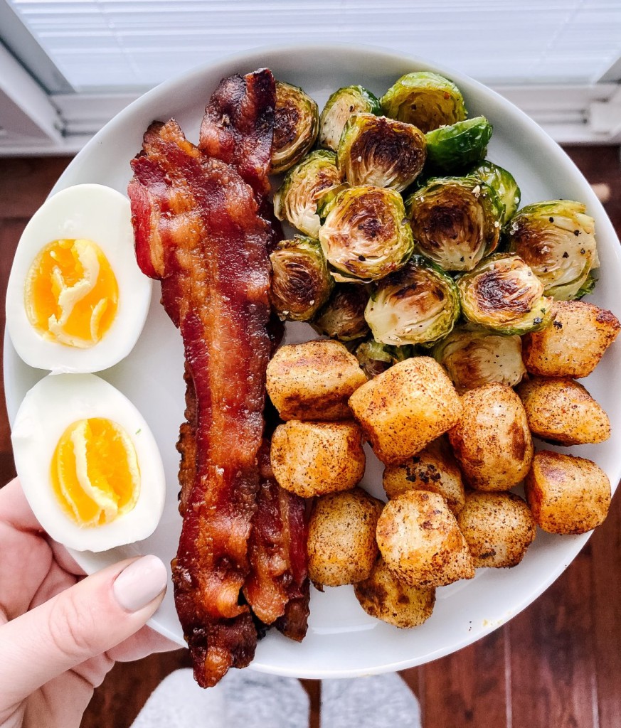 roasted brussels sprouts on a breakfast plate with bacon and hard boiled eggs