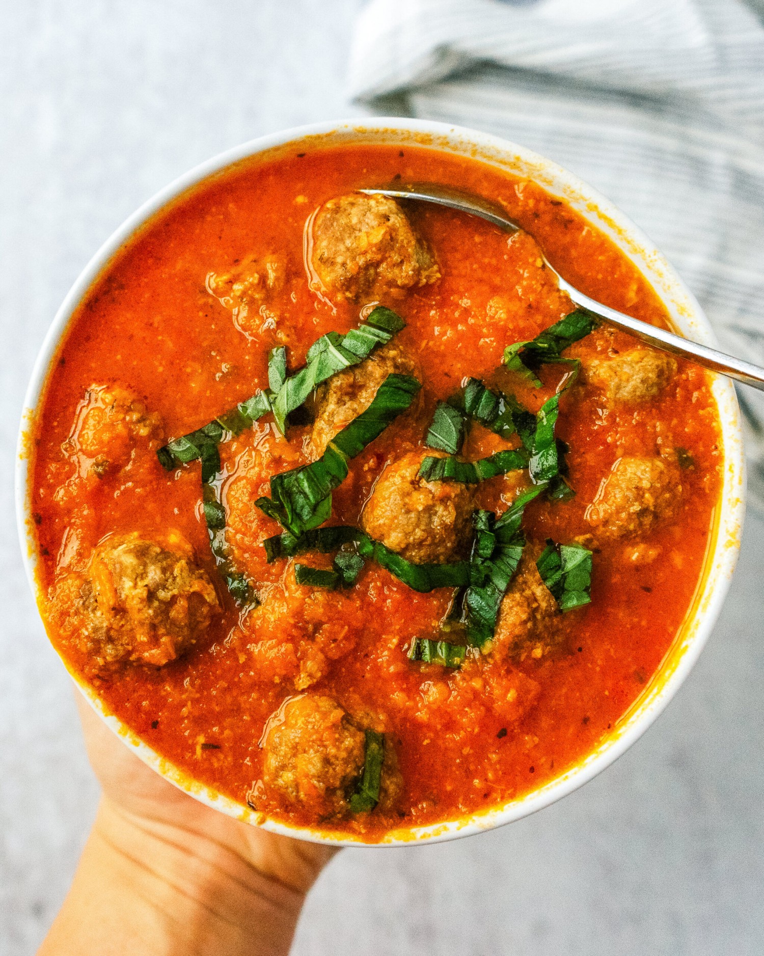 Above view of a bowl of tomato basil meatball soup made with mini beef meatballs