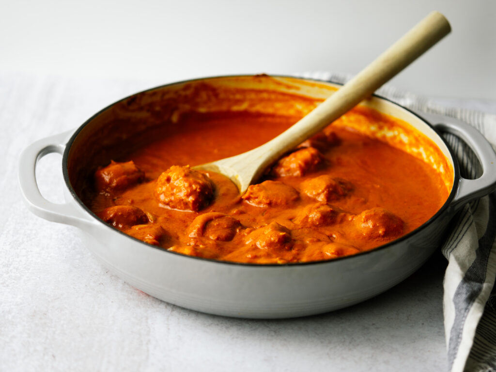 side view of baked chicken meatballs in a tikka masala sauce