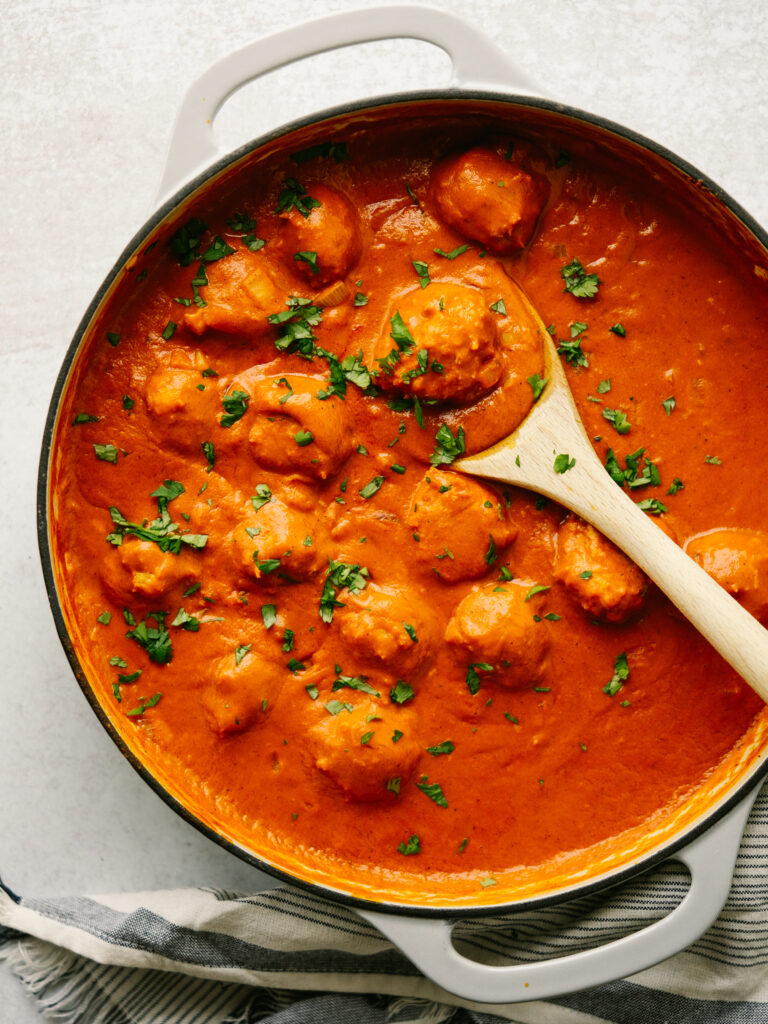 Above view of chicken tikka meatballs in a pan with a spoon in it