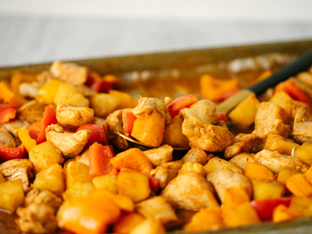 Three quarter view of pineapple chicken with peppers on a sheet pan