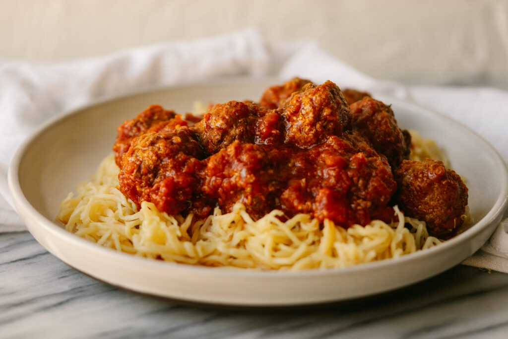 Side view of Instant Pot meatballs on a plate of spaghetti