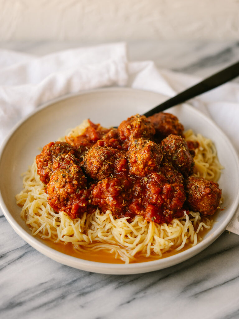 Three quarter view of simple beef meatballs on a plate of spaghetti