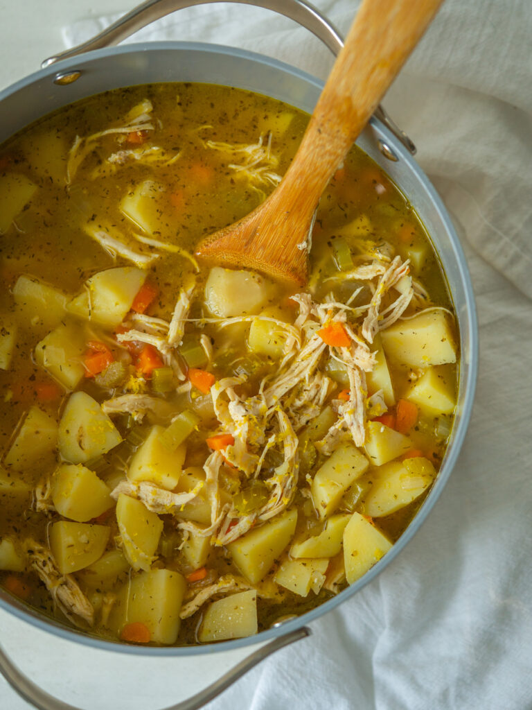 Above view of lemon chicken soup with potatoes in a large stock pot 