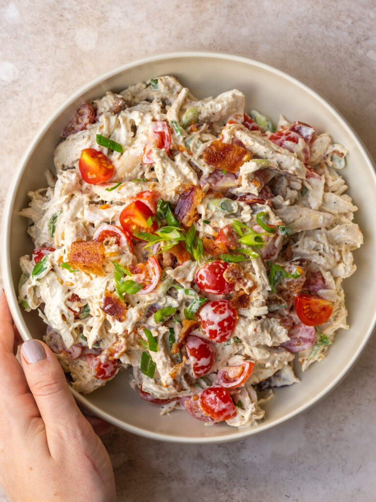 bowl of BLT chicken salad with a hand on the side