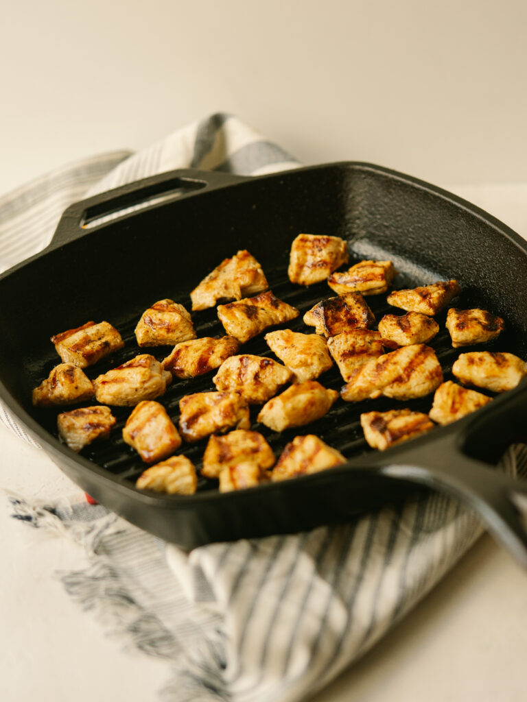a three quarter view photo of grilled chicken nuggets in a grill pan