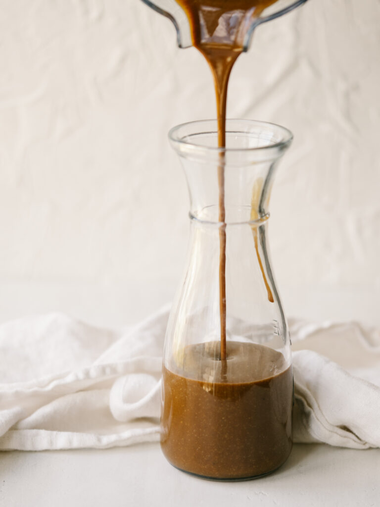 creamy balsamic vinaigrette pouring from  a blender in a glass jar