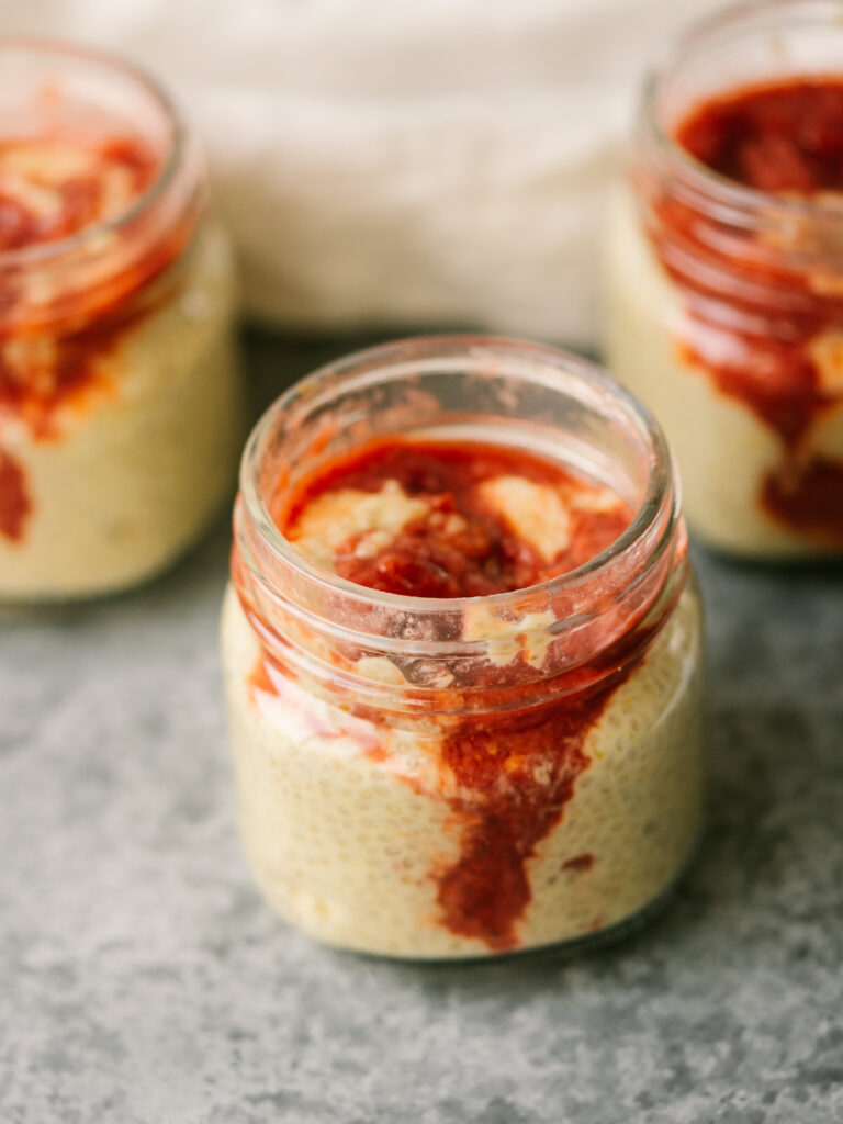 Three quarter above view of jars of mango chia seed pudding with strawberry compote on top