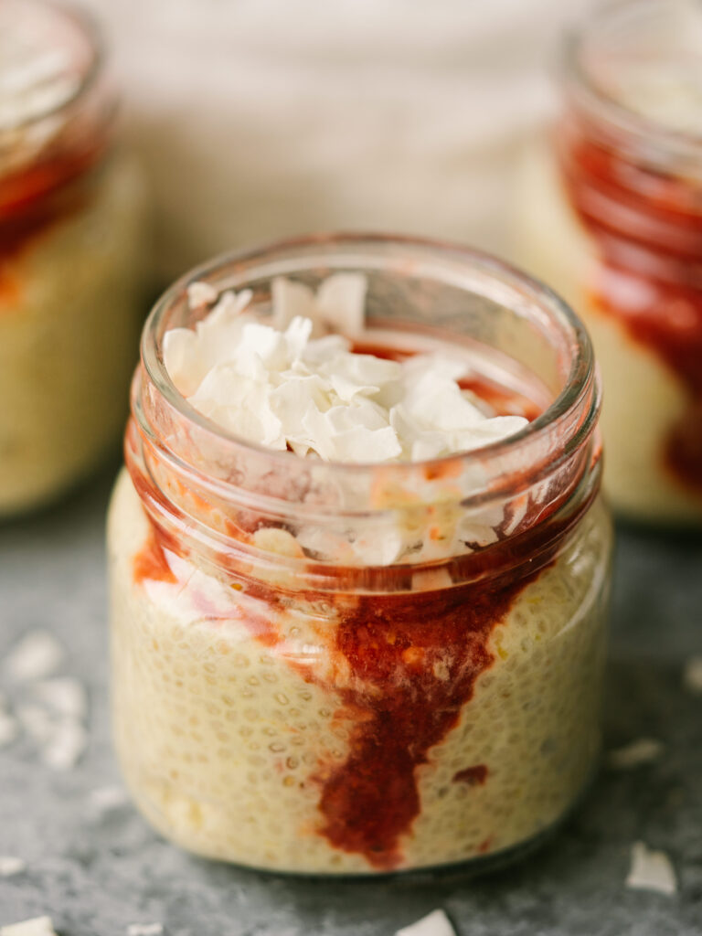 Strawberry mango chia seed pudding in a glass jar with coconut chips on top