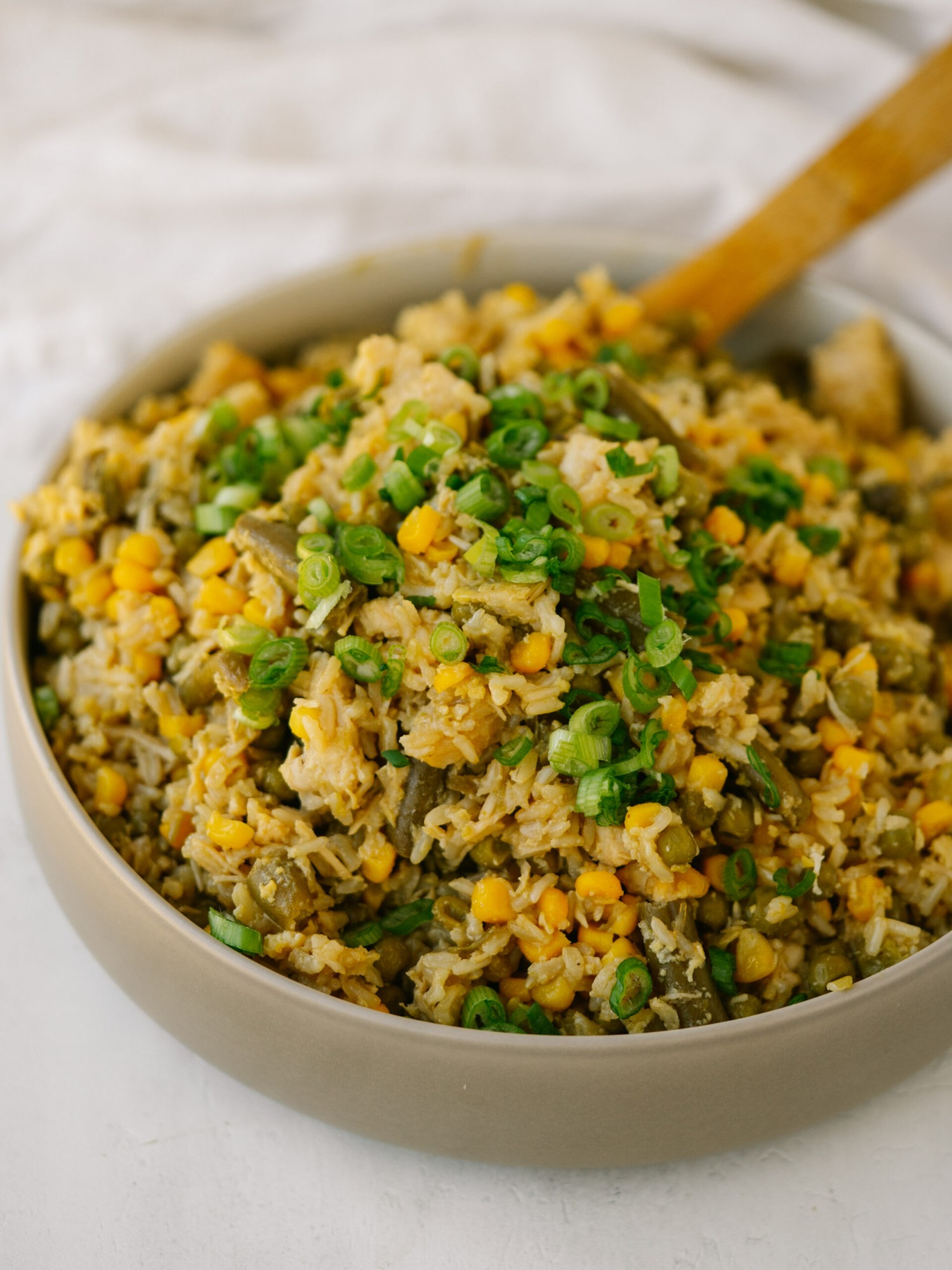 a three quarter view photo of pantry fried rice in a bowl with a wooden spoon