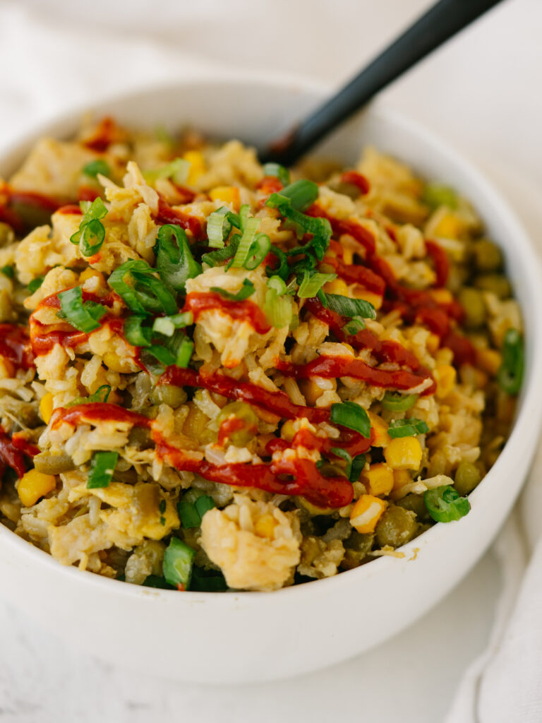a close up photo of pantry fried rice with sriracha on top