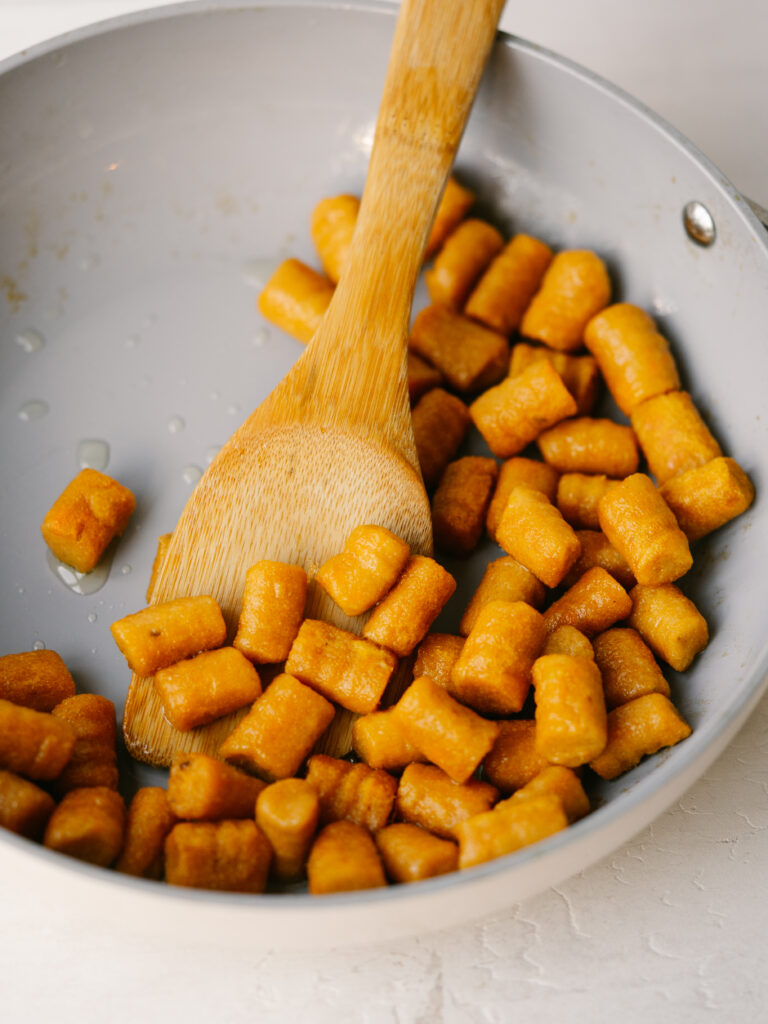 overhead view of sweet potato gnocchi in a pan with a spoon