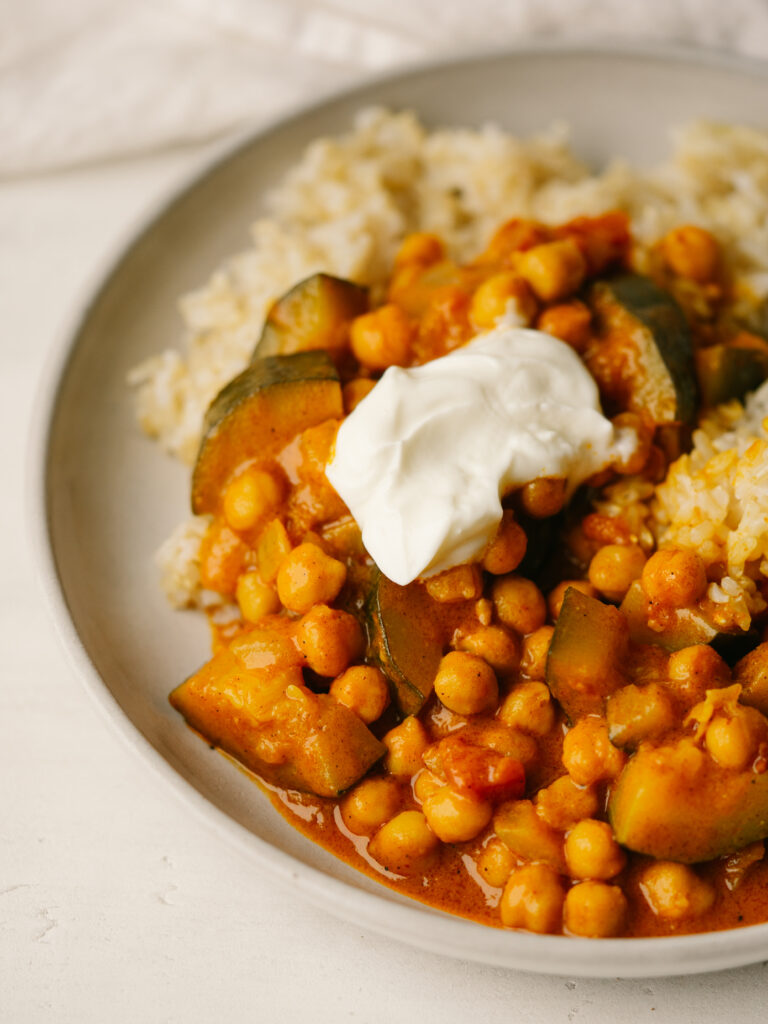 Three quarter view of chickpea stew on a plate with a dollop of sour cream