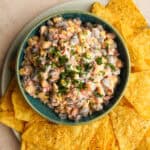 black bean and corn dip in a green bowl on a plate with tortilla chips