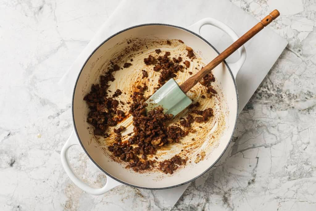 seasonings being mixed into onion and garlic mixture in a skillet