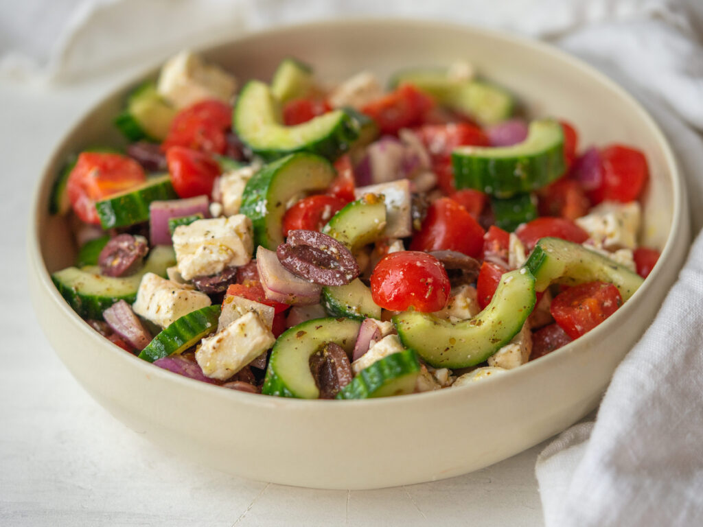 three quarter view of a tossed easy greek salad recipe in a bowl