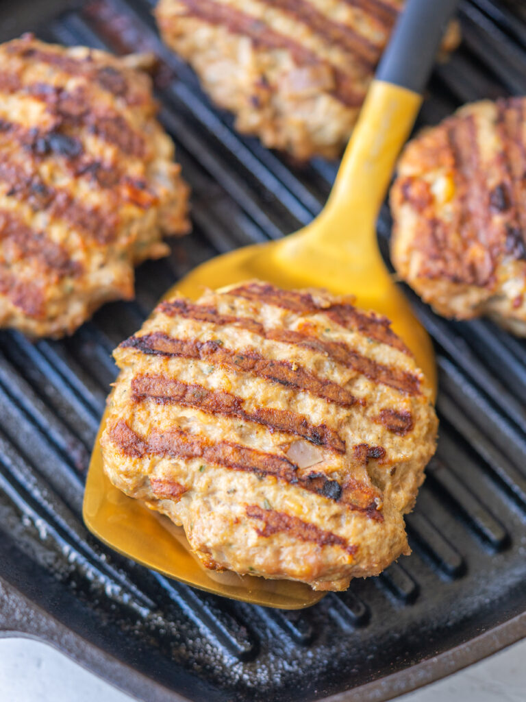 ground turkey burger on a spatula with grill marks