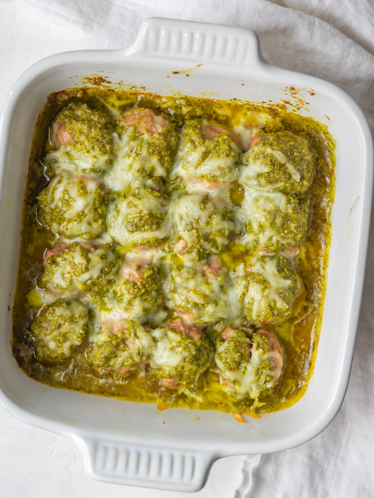 Above view of cooked pesto meatballs in a baking dish