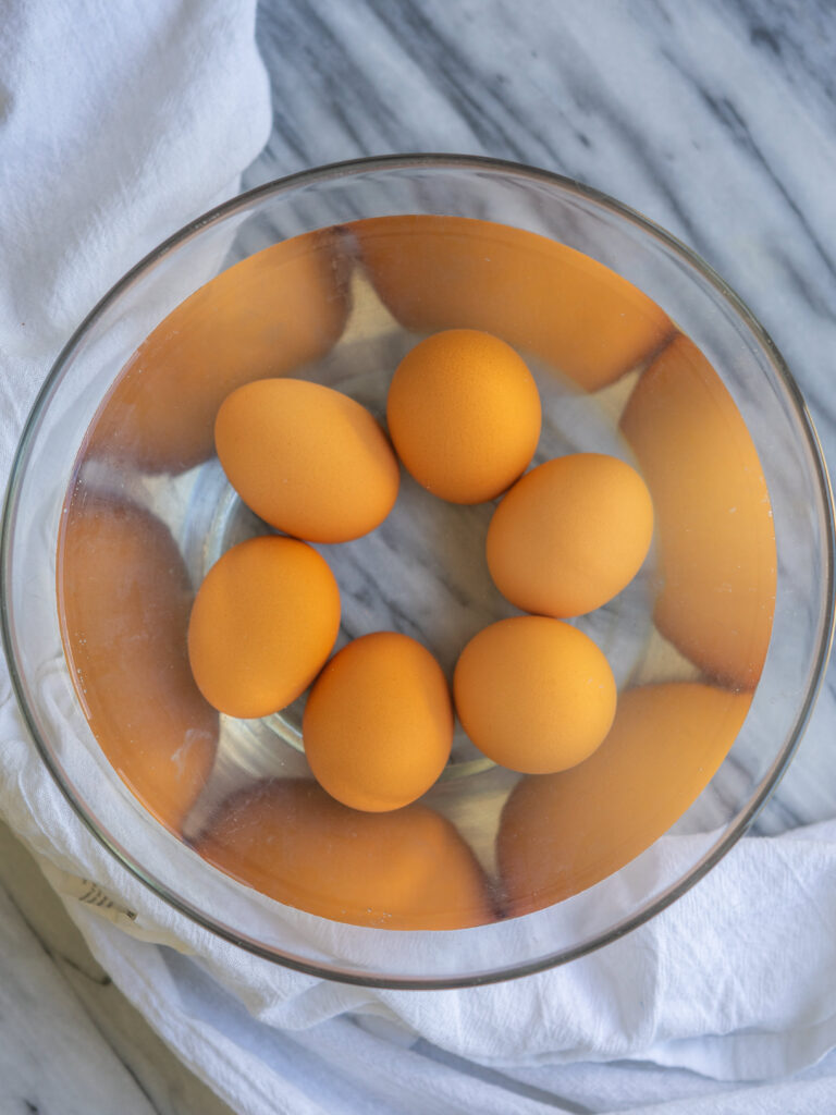 overhead view of hard boiled eggs in a bowl of water