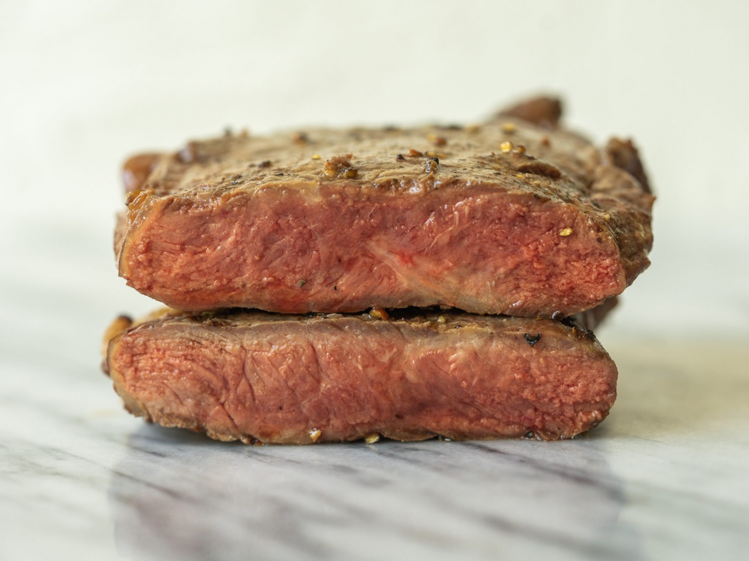 a side view photo of two halves of a steak stacked on top of one another