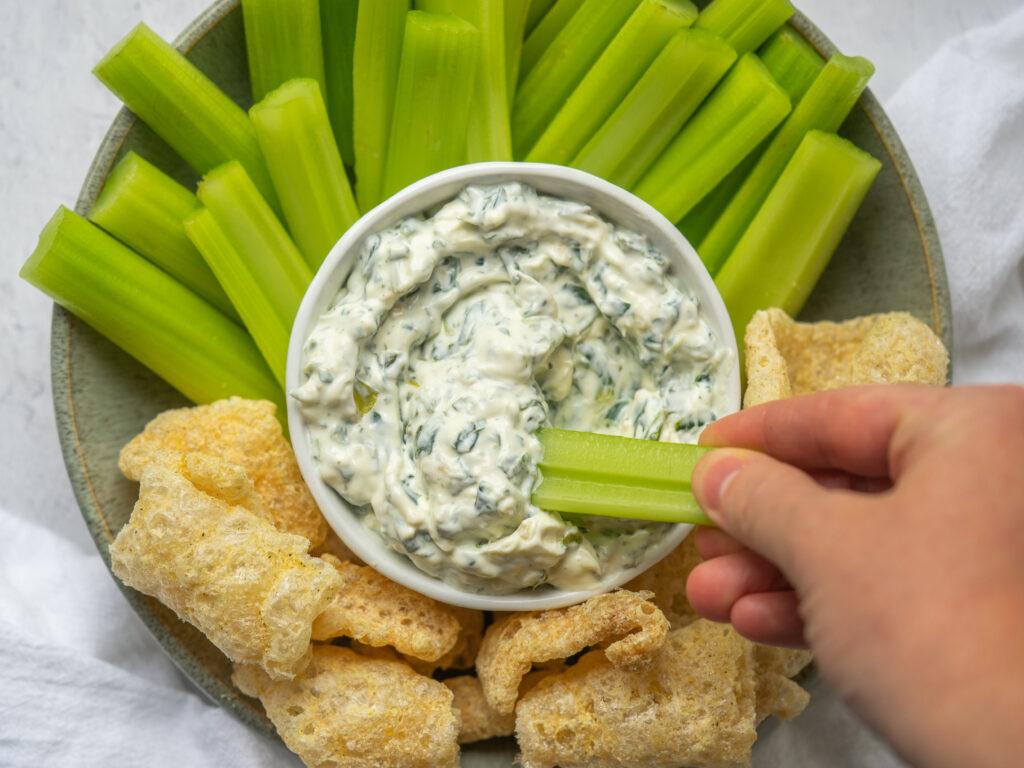Above view of a piece of celery dipping into an Easy Spinach Dip