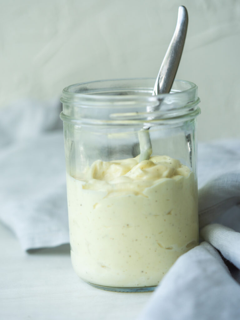 Side view of homemade avocado oil mayo in a mason jar