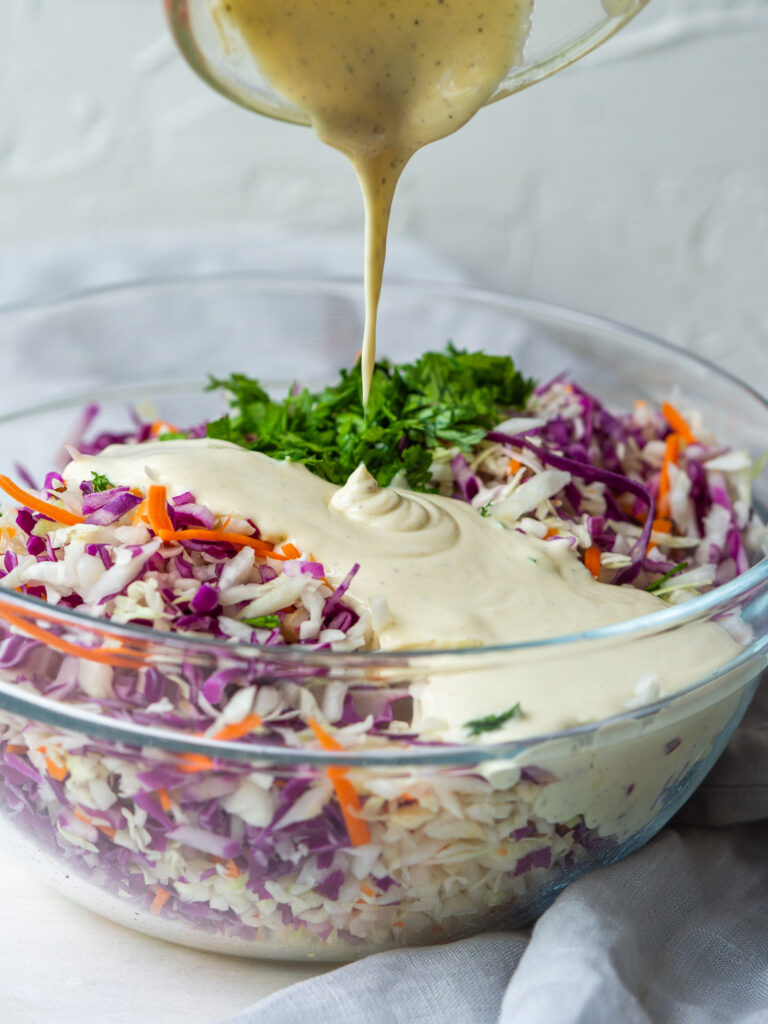 Close up three quarter view of creamy coleslaw ingredients in a large mixing bowl
