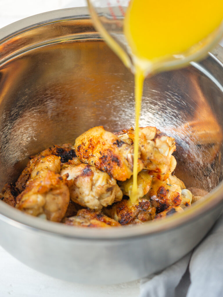 Lemon butter sauce being poured over grilled chicken wings