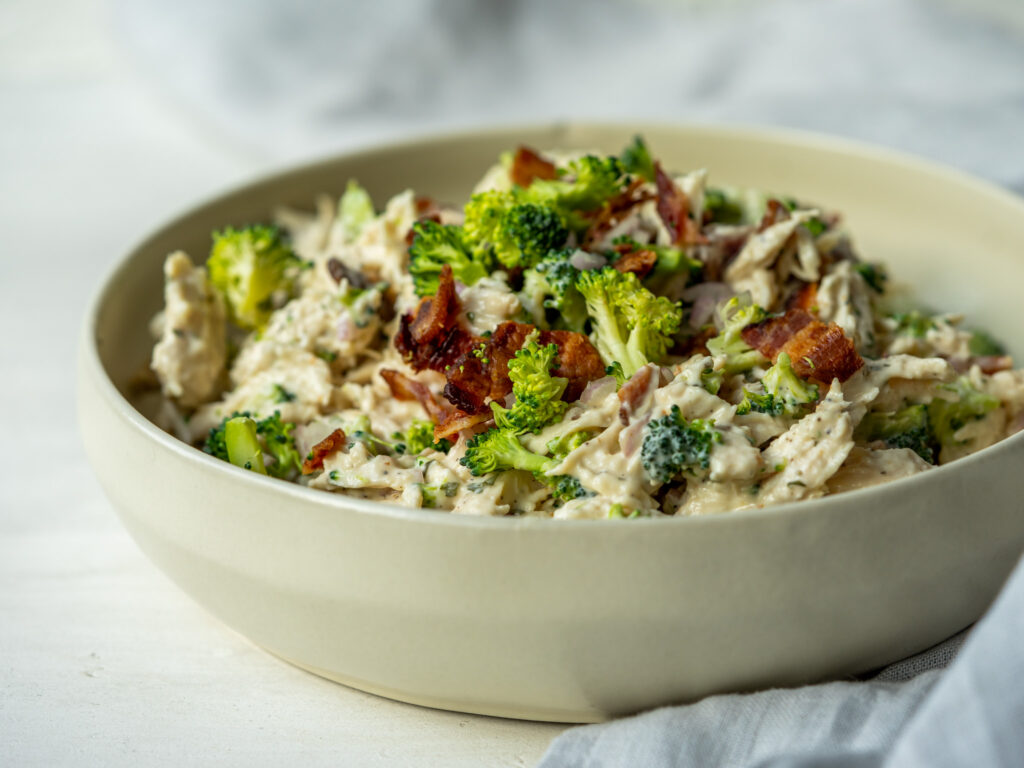 Side view of bacon broccoli and ranch chicken salad in a mixing bowl