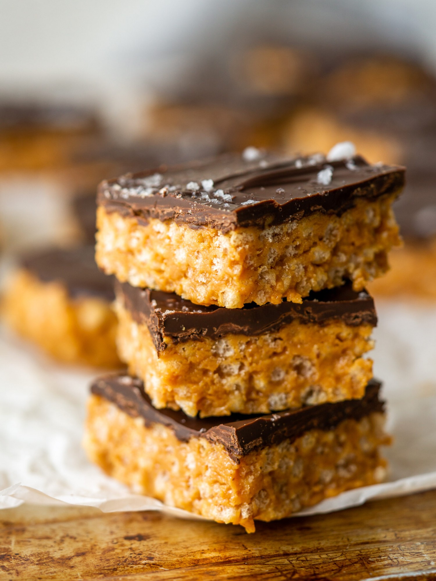 Side view of peanut butter rice krispie treats stacked up on a piece of parchment paper
