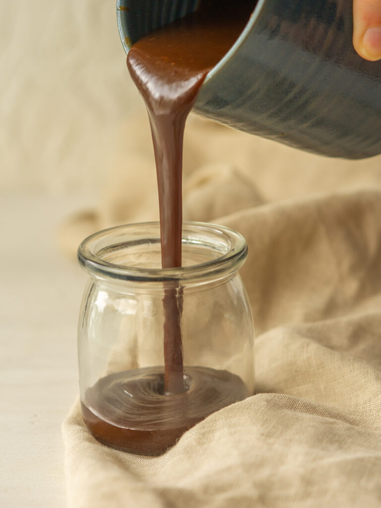 Side view of copycat Starbucks pumpkin spice syrup pouring into a glass jar